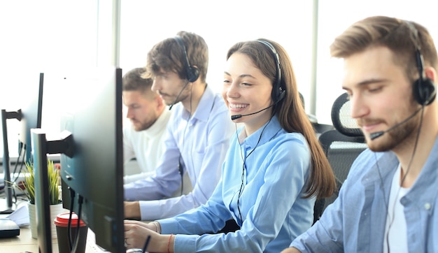 Portret pracownika call center w towarzystwie swojego zespołu. Uśmiechnięty operator obsługi klienta w pracy.