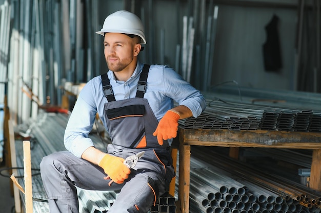 Portret pracownika fabryki w mundurze ochronnym i kasku stojącym przy maszynie przemysłowej na linii produkcyjnej Osoby pracujące w przemyśle