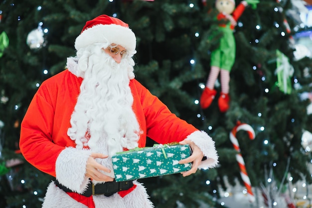 Portret prawdziwego autentycznego Świętego Mikołaja z prezentami świątecznymi w rękach w centrum handlowym