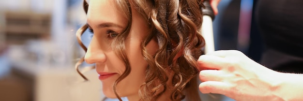 Portret profesjonalnego fryzjera używającego lokówki kobiecej tworzącej piękny luksus