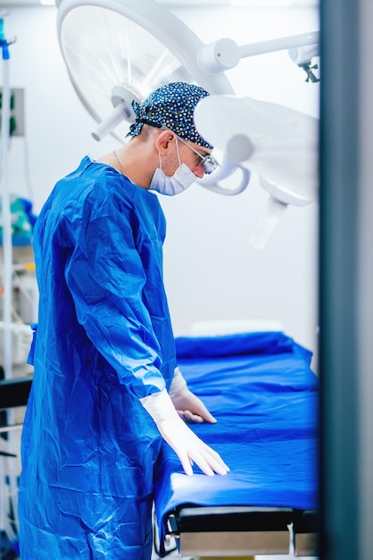 Portret profesjonalnego lekarza chirurga plastycznego przygotowującego się do operacji i noszącego sterylne fartuchy