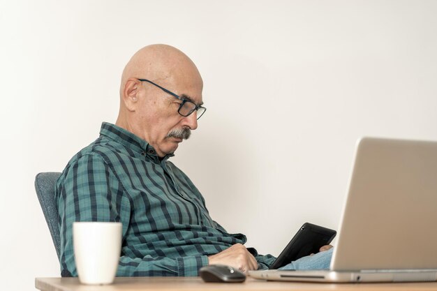 Portret Profesjonalnego Mężczyzny Siedzącego Przed Laptopem W Biurze I Przy Użyciu Cyfrowego Tabletu W Drugiej Ręce.