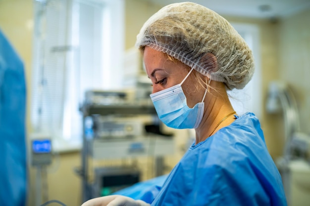 Portret profesjonalnej asystentki medycznej pielęgniarki w masce chirurgicznej podczas operacji Nowoczesna szpitalna sala operacyjna