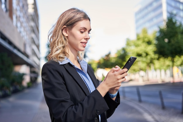 Portret Profilowy Młodej Sprzedawczyni Korporacyjnej Damy W Garniturze Za Pomocą Telefonu Komórkowego Czytającego Na Smartfonie