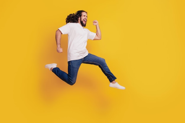 Portret profilowy śmiesznego pozytywnego dorywczo marzycielskiego faceta biegnącego szybko pośpiechu skaczącego na żółtym tle