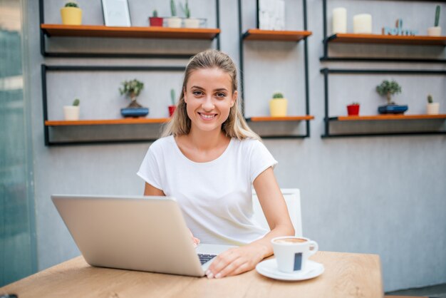 Portret przypadkowa młoda kobieta z laptopem w kawiarni.
