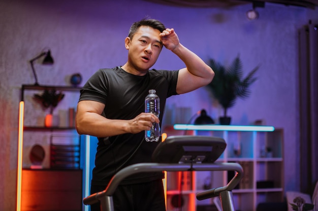 Portret przystojnego, aktywnego, spragnionego i dynamicznego młodego azjatyckiego mężczyzny uprawiającego fitness sportowy w domu
