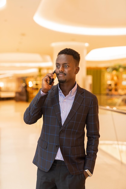 Portret przystojnego czarnego biznesmena przy użyciu telefonu komórkowego