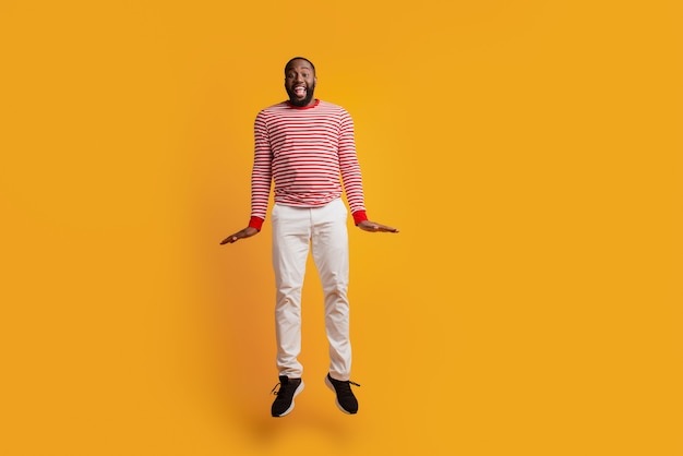 Portret przystojnego mężczyzny skaczącego nosić swobodny strój na żółtym tle
