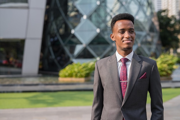 Portret przystojnego młodego afrykańskiego biznesmena na zewnątrz w mieście