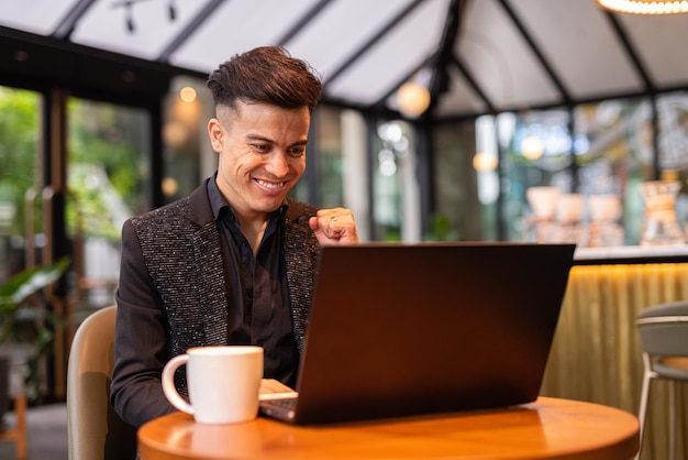 Portret przystojnego młodego biznesmena korzystającego z laptopa w kawiarni