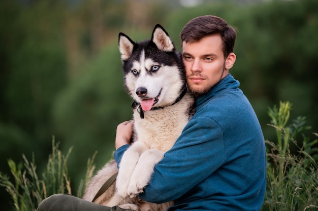 Portret przystojnego młodzieńca i jego psa Siberian Husky w przyrodzie