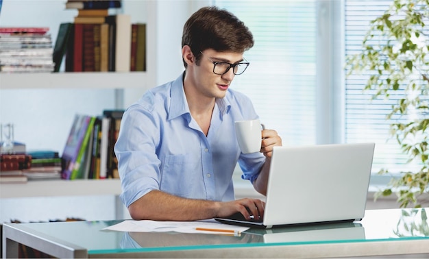 Portret przystojny biznesmen używa laptop dalej