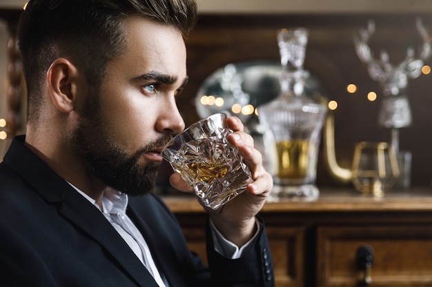 Zdjęcie portret przystojny brodaty mężczyzna ze szklanką whisky
