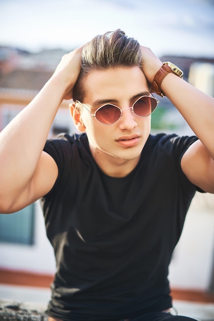 Zdjęcie portret przystojny młody człowiek w czarnej koszulce i moda okulary przeciwsłoneczne