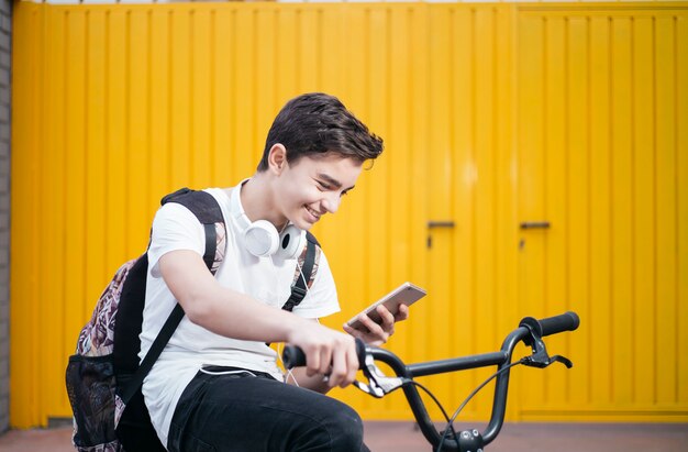 Portret Przystojny nastolatek uśmiecha się, gdy używa swojego mobil