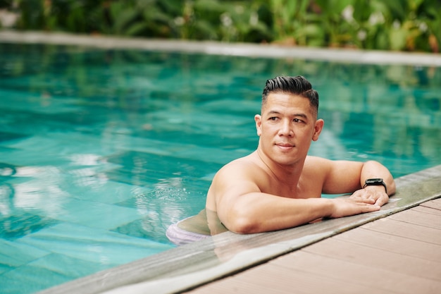 Portret przystojny sprawny muskularny mężczyzna stojący w basenie i odwracający wzrok