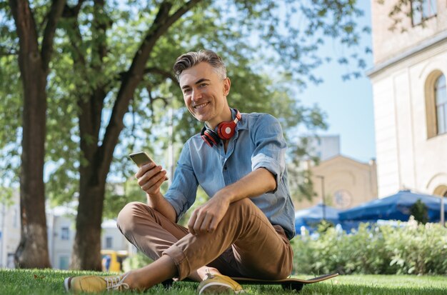 Portret przystojny uśmiechnięty mężczyzna trzyma telefon komórkowy