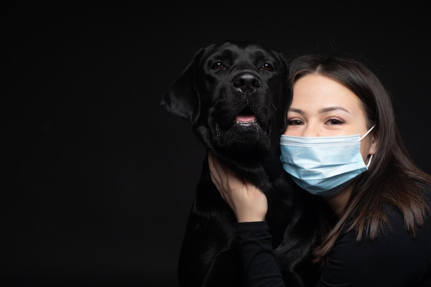 Portret psa Labrador Retriever w ochronnej masce medycznej z właścicielką Zdjęcie zostało zrobione na zdjęciu Studio