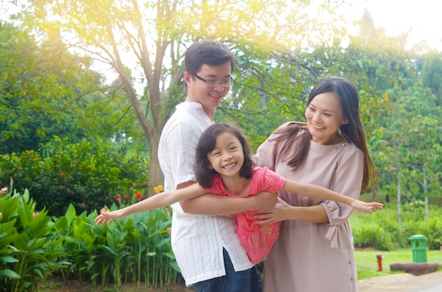 Portret radosna szczęśliwa Azjatycka rodzina bawić się wpólnie przy plenerowym parkiem podczas lato zmierzchu.