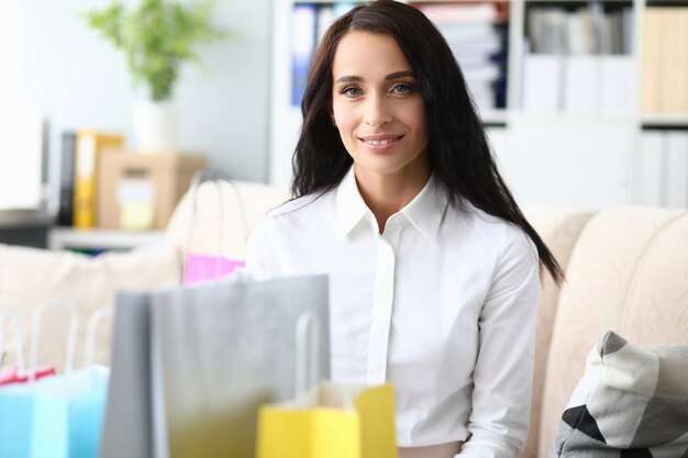 Portret radosny bizneswoman siedzi blisko stubarwnych paczek.