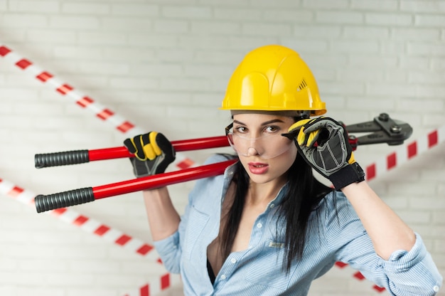 Zdjęcie portret robotnicy budowlanej w kasku z przecinakiem do śrub w dłoniach