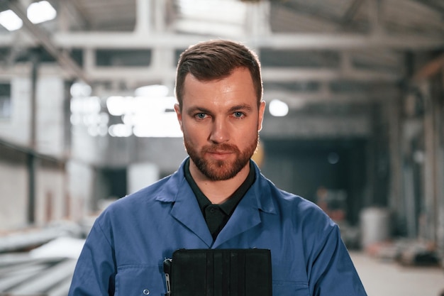 Zdjęcie portret robotnika fabrycznego w niebieskim mundurze w pomieszczeniu