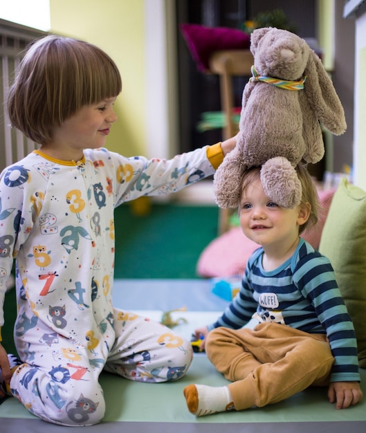 Zdjęcie portret rodzeństwa bawiącego się z pluszowym niedźwiedziem w domu