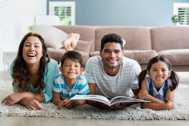 Portret rodziców i dzieci leżących na dywanie i czytanie książki
