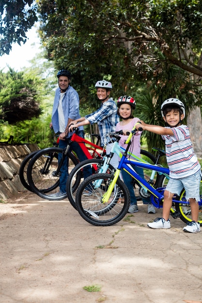 Portret rodziców i dzieci stojących z rowerem w parku