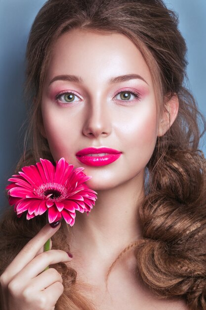 Portret romantyczna młoda kobieta z różowym kwiatu patrzeć. Fotografia mody wiosennej. Inspiracja wiosną i latem.