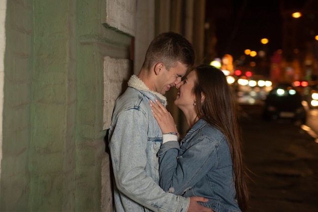 Portret roześmiana młoda para i całowanie na tle miasta w nocy. Romantyczna data. młoda para w miłości.