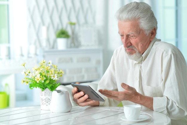 Portret rozważnego starszego mężczyzny korzystającego z tabletu