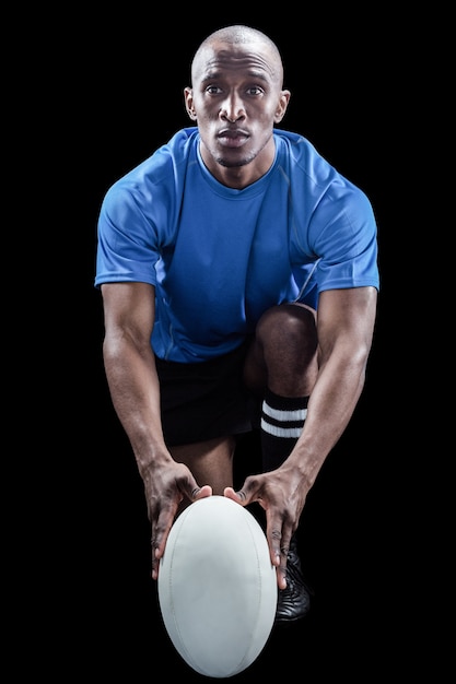Portret rugby gracza mienia piłka podczas gdy klęczący