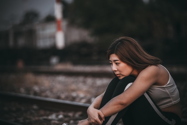 Portret samotnej kobiety samotnej na linii kolejowej Styl vintage z filtremzłamane serce z koncepcji miłosnej smutnej dziewczyny w stylu vintage o zachodzie słońca