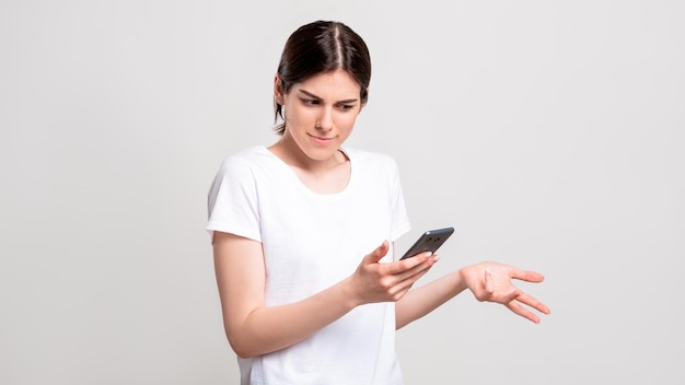 Portret sceptycznej kobiety Niewłaściwa oferta Wątpliwa dama czytająca wiadomość na telefonie z wtf wzruszając ramionami na białym tle na białej kopii miejsca Spam mobilny