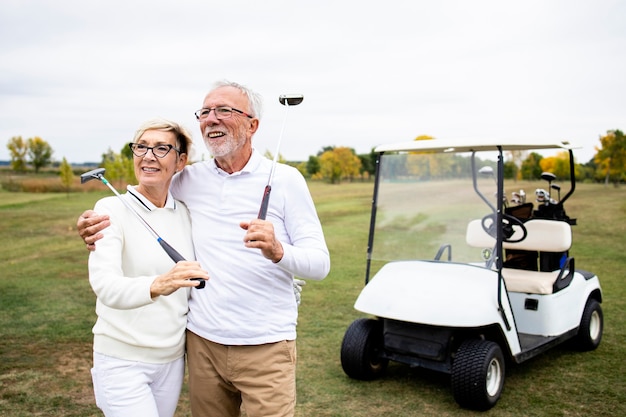 Portret senior para korzystających z emerytury, grając w golfa na polu golfowym.