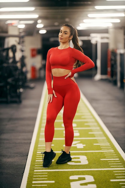 Portret silnej sportowki stojącej w siłowni i patrzącej na kamerę