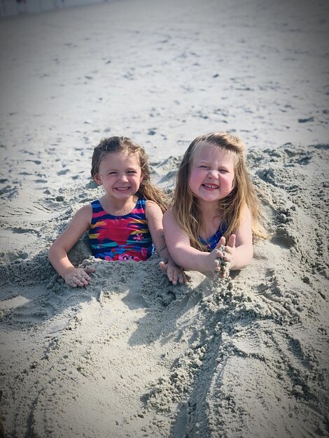 Zdjęcie portret sióstr bawiących się piaskiem na plaży