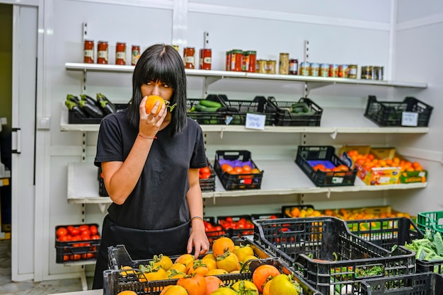 Portret sklepikarza w warzywniaku wąchającego dojrzałą persimmon