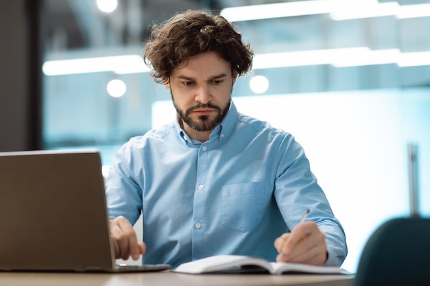 Portret skoncentrowanego biznesmena używającego laptopa i pisania