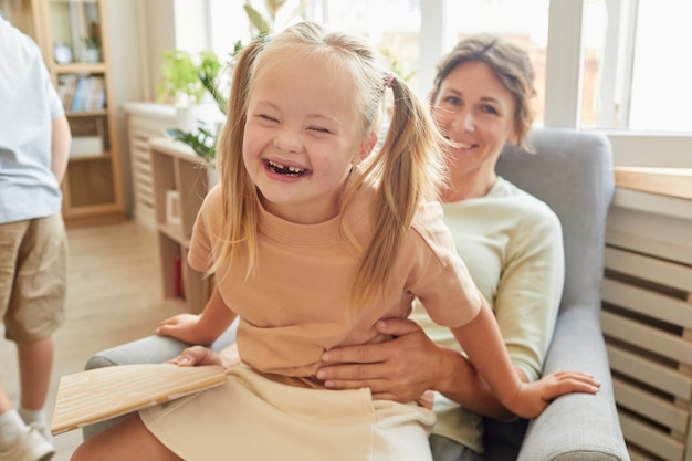 Portret śliczna dziewczyna z zespołem Downa śmiejąca się radośnie podczas zabawy z matką w domu