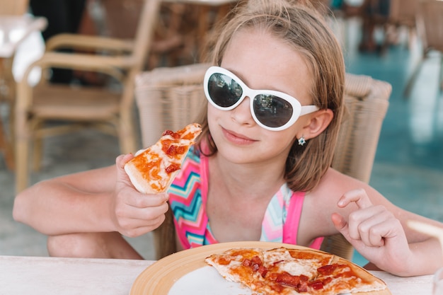 Portret śliczna Małej Dziewczynki Obsiadanie Obiadowym Stołem I Jeść Pizzę