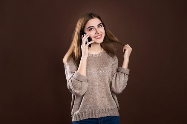 Portret śliczna szczęśliwa dziewczyna opowiada na telefonie komórkowym w pulowerze