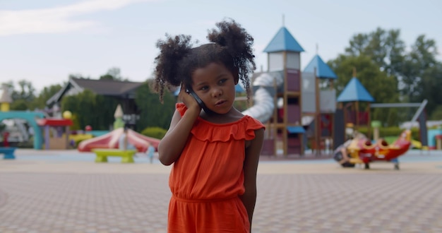 Portret ślicznej afrykańskiej dziewczynki dzwoniącej przez telefon komórkowy na zewnątrz
