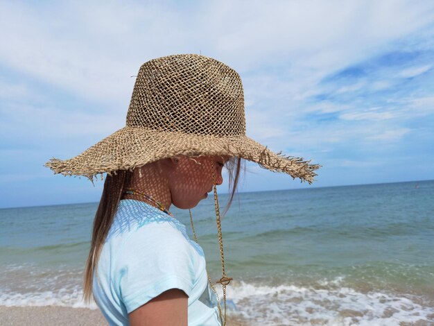 Portret ślicznej dziewczynki w słomkowym kapeluszu na plaży w słoneczny letni dzień