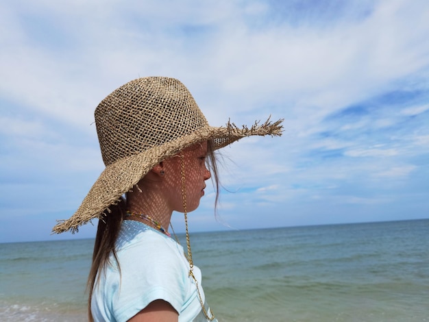 Portret ślicznej dziewczynki w słomkowym kapeluszu na plaży w słoneczny letni dzień