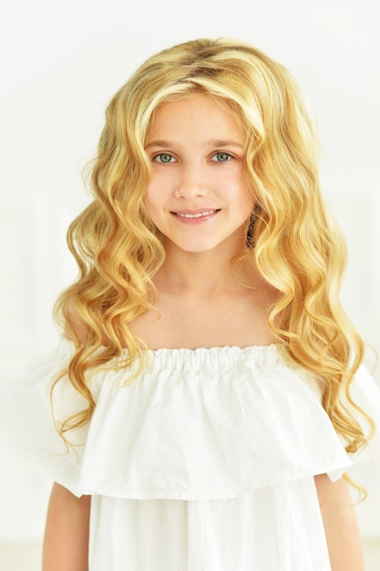 Portret ślicznej małej dziewczynki pozuje w białej sukni