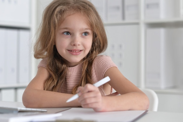 Portret ślicznej małej studentki odrabiającej pracę domową