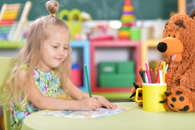 Zdjęcie portret ślicznej pięknej małej dziewczynki rysującej przy stole